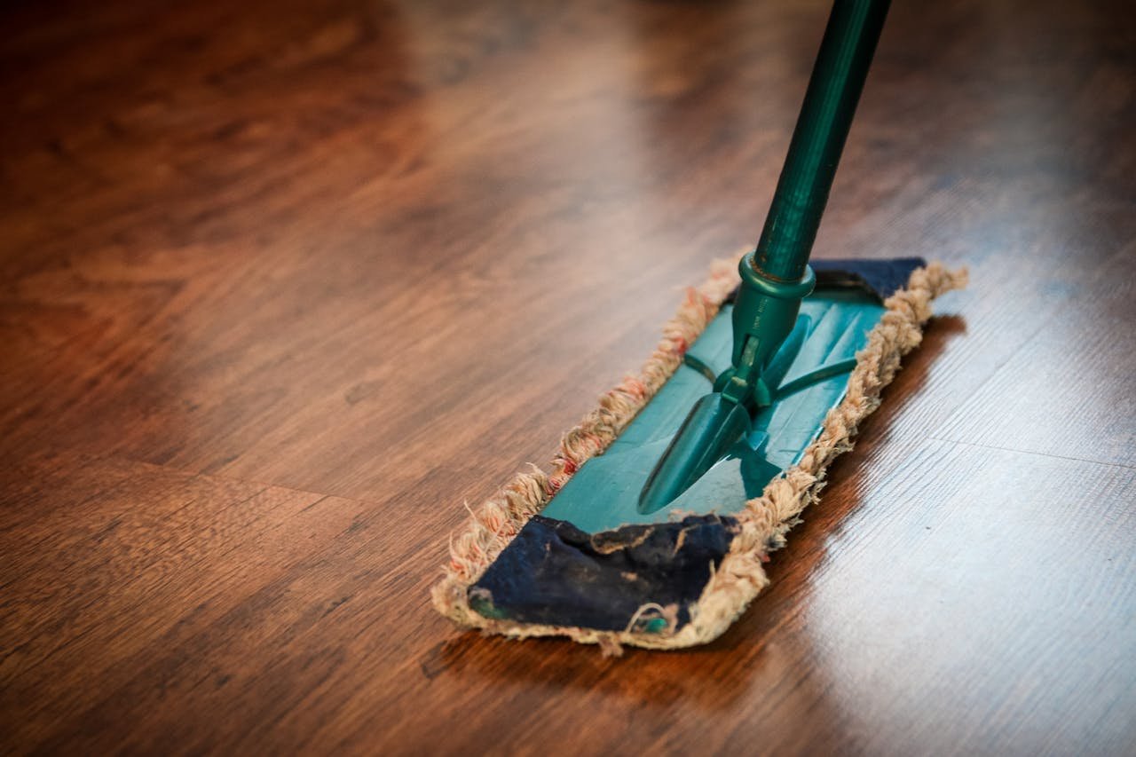 A detailed view of a mop cleaning a wooden floor, showing texture and pattern.